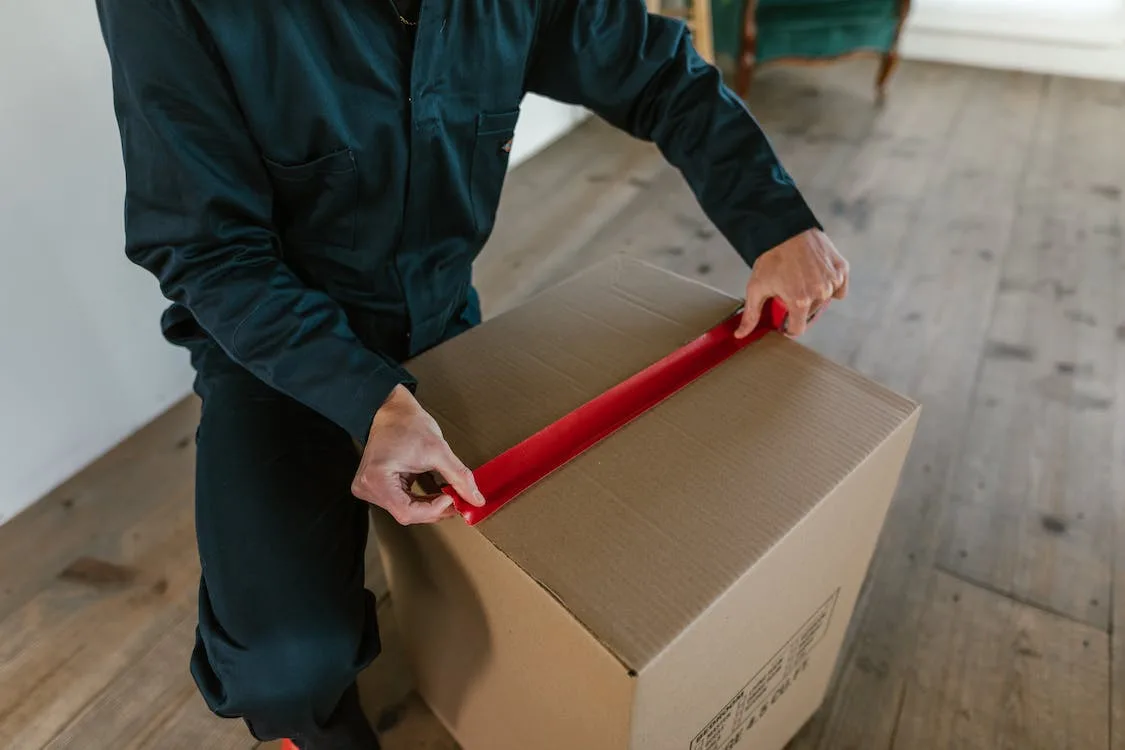 Free A Man Sealing a Cardboard Box With Masking Tape Stock Photo