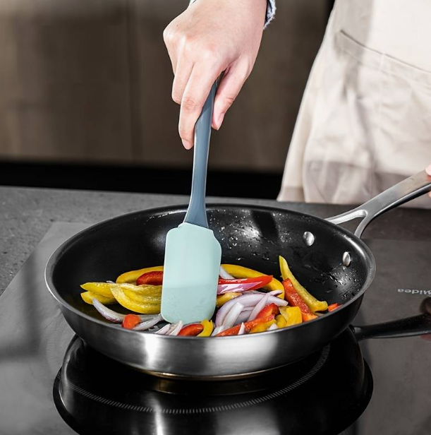 A person cooking vegetables in a pan

Description automatically generated